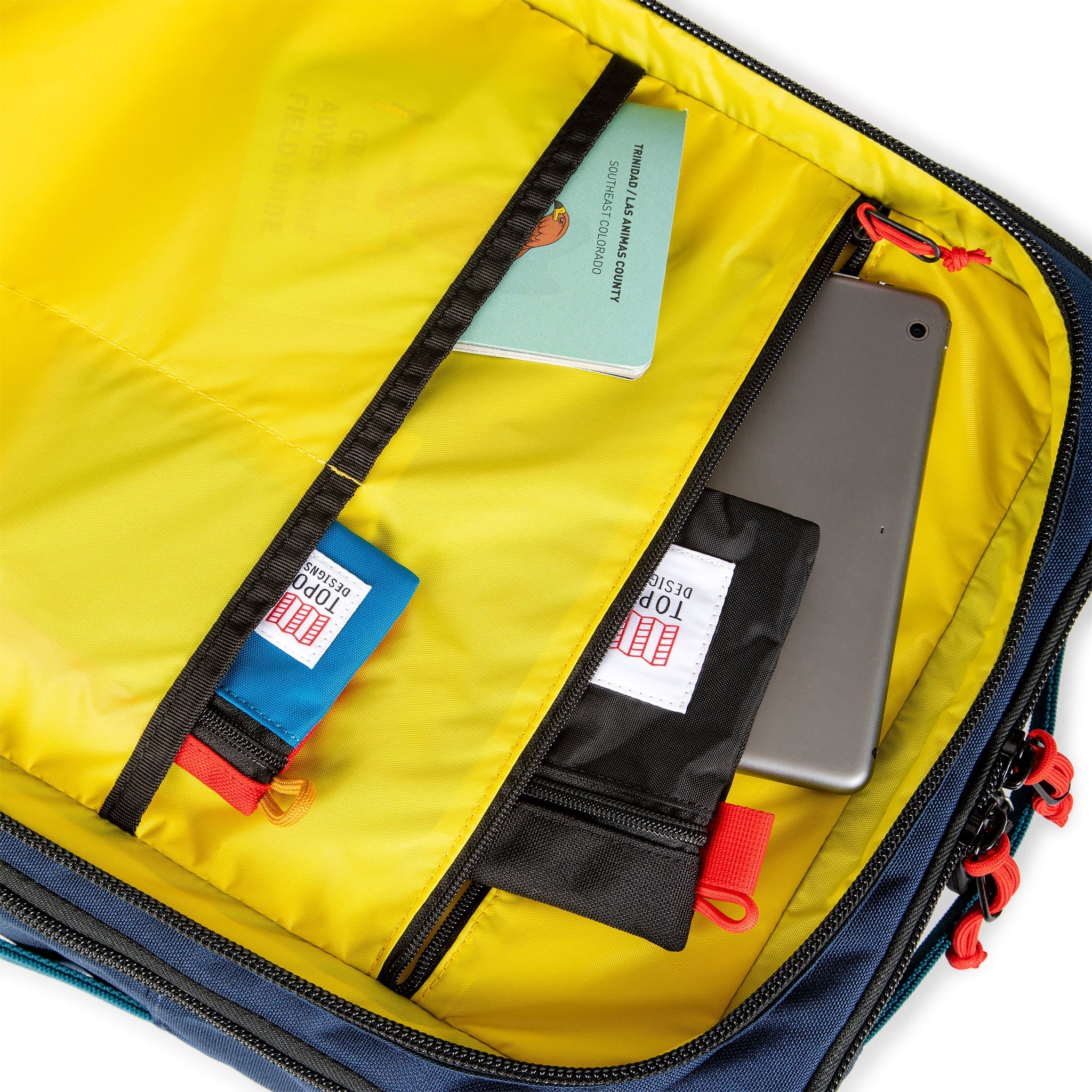 Yellow interior pockets of Topo Designs Global Travel Bag 40L Durable Carry On Convertible Laptop Travel Backpack in Navy blue.