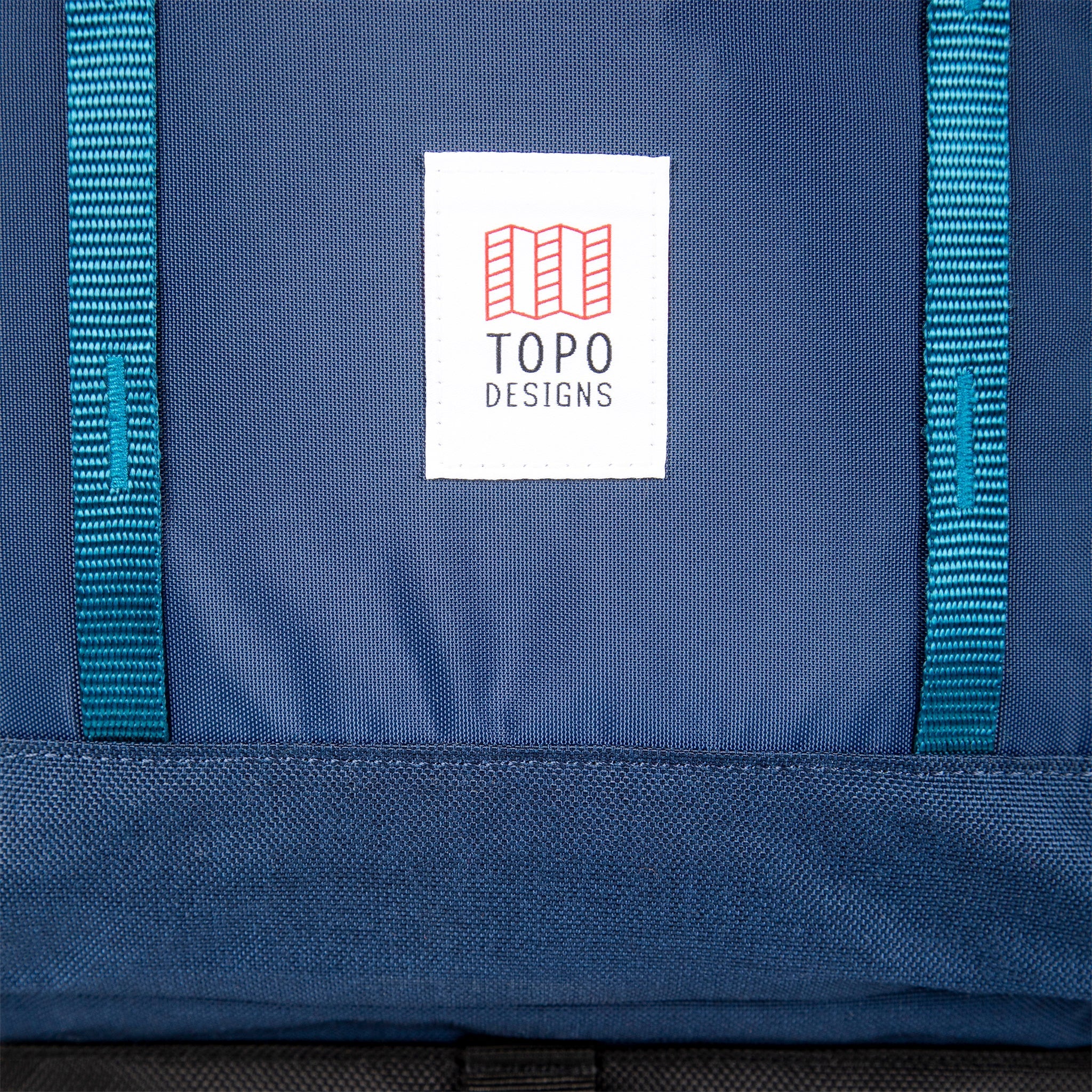 Topo Designs logo patch and front daisy chain webbing on Global Travel Bag 40L Durable Carry On Convertible Laptop Travel Backpack in Navy blue.