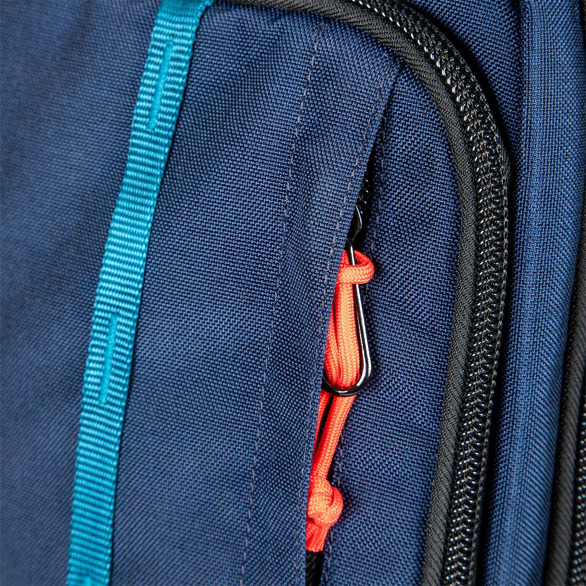 Front zipper pocket & daisy chain on Topo Designs Global Travel Bag Roller durable carry-on convertible laptop rolling backpack suitcase in Navy blue.