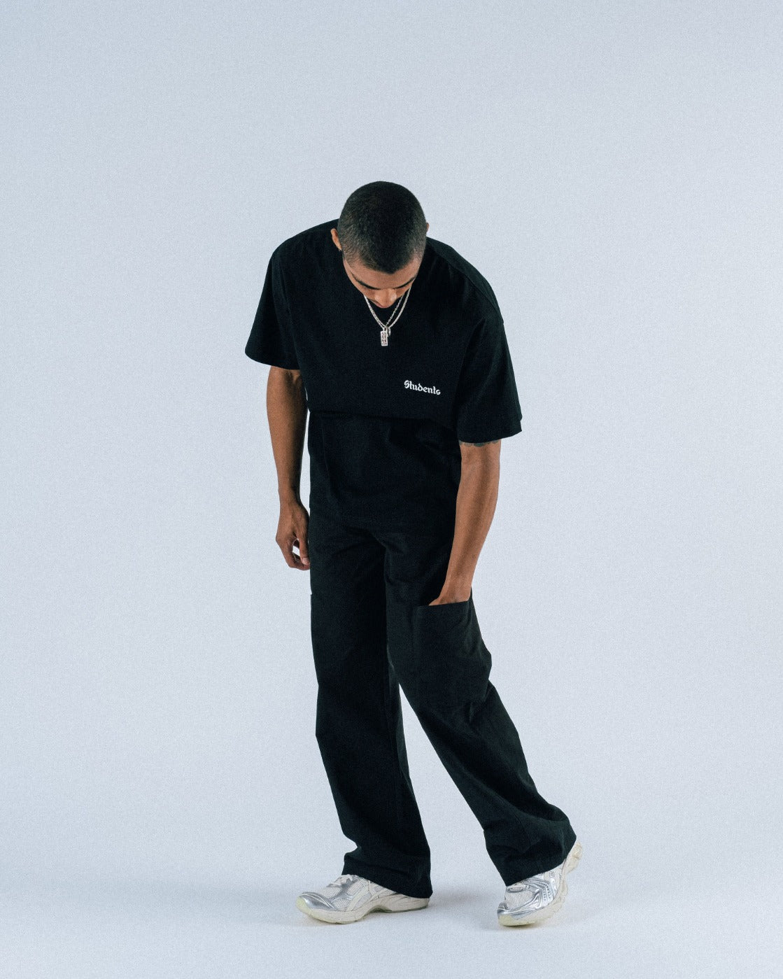 Person wearing a black outfit with a brand logo on a white background