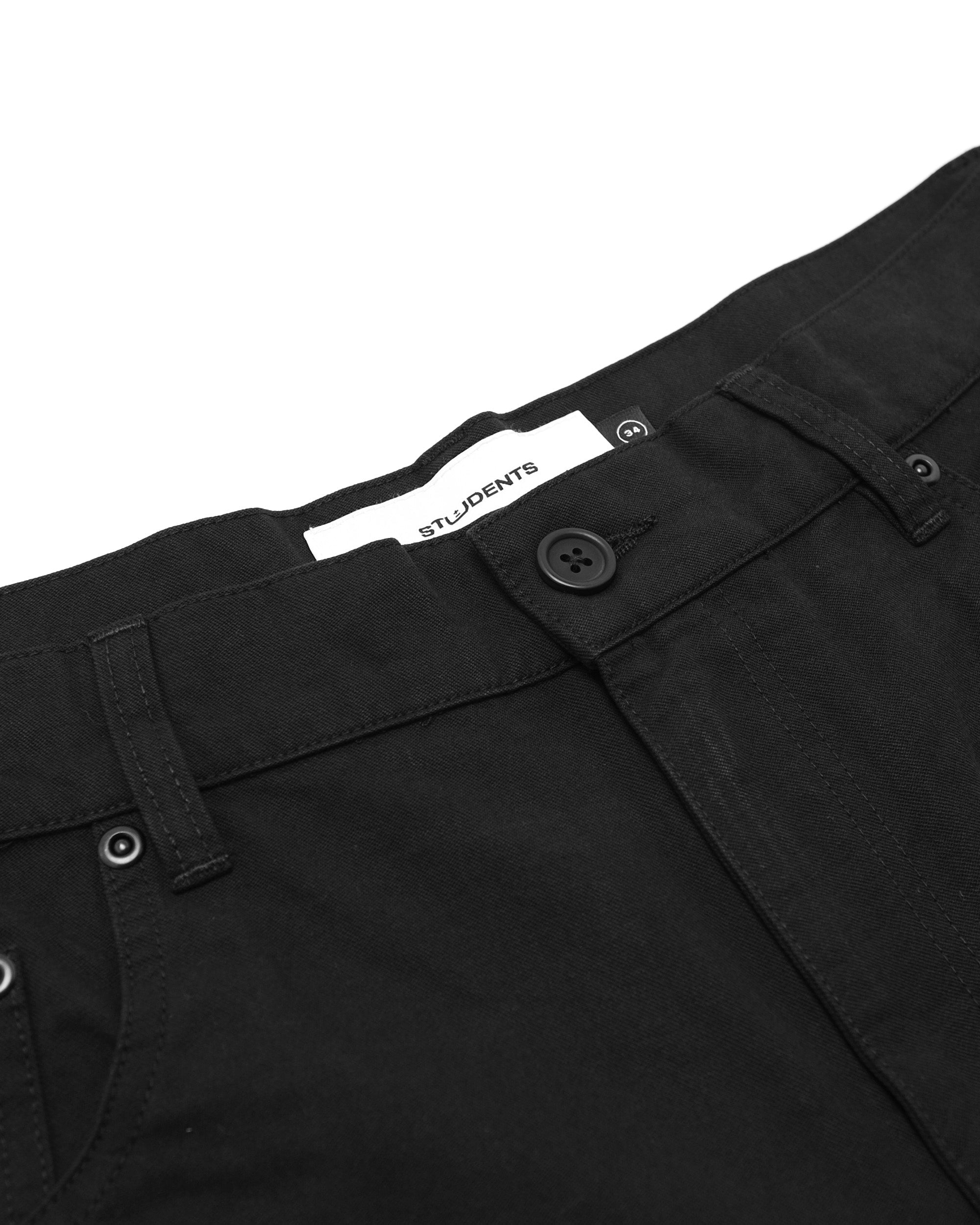 Close-up of black pants with a visible brand label on a white background