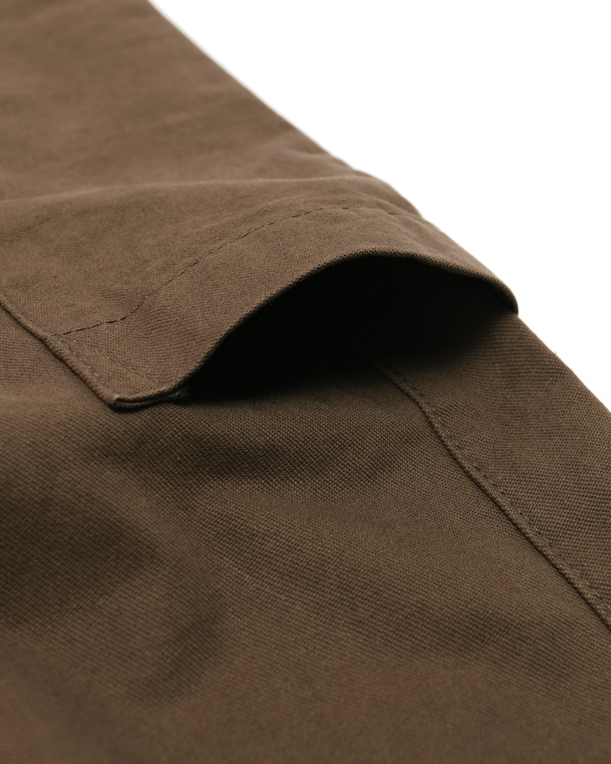 Close-up of brown fabric with a pocket detail on a white background