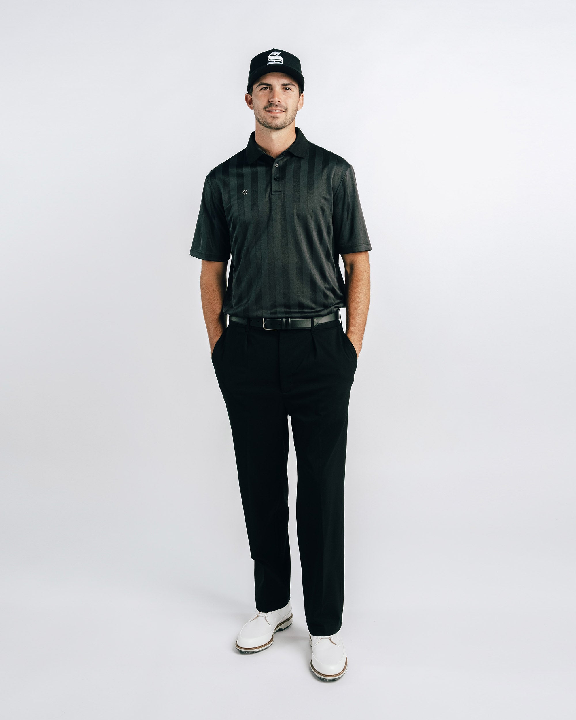 Man wearing a black golf outfit with a cap on a white background