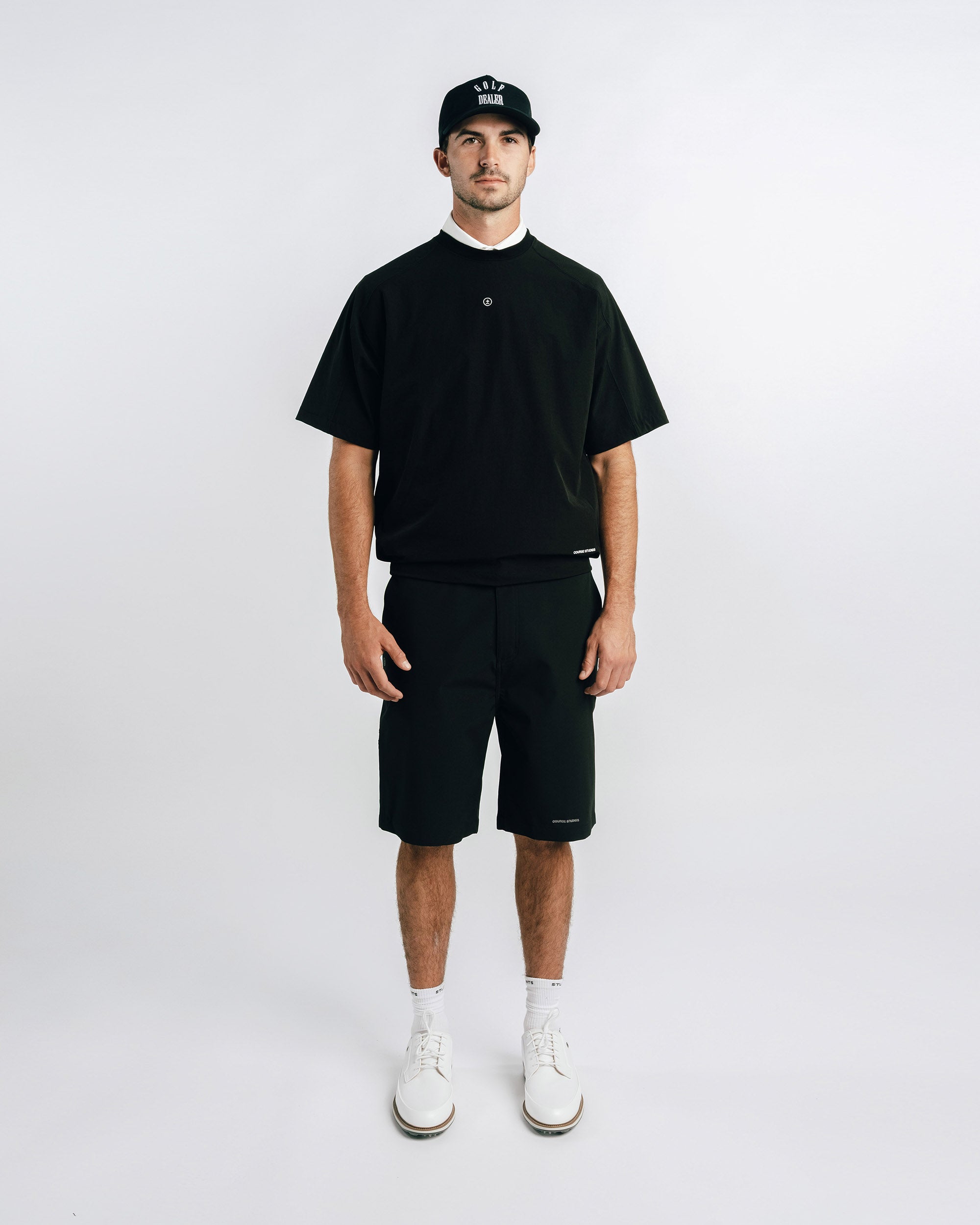 Man wearing a black t-shirt, shorts, and cap on a white background