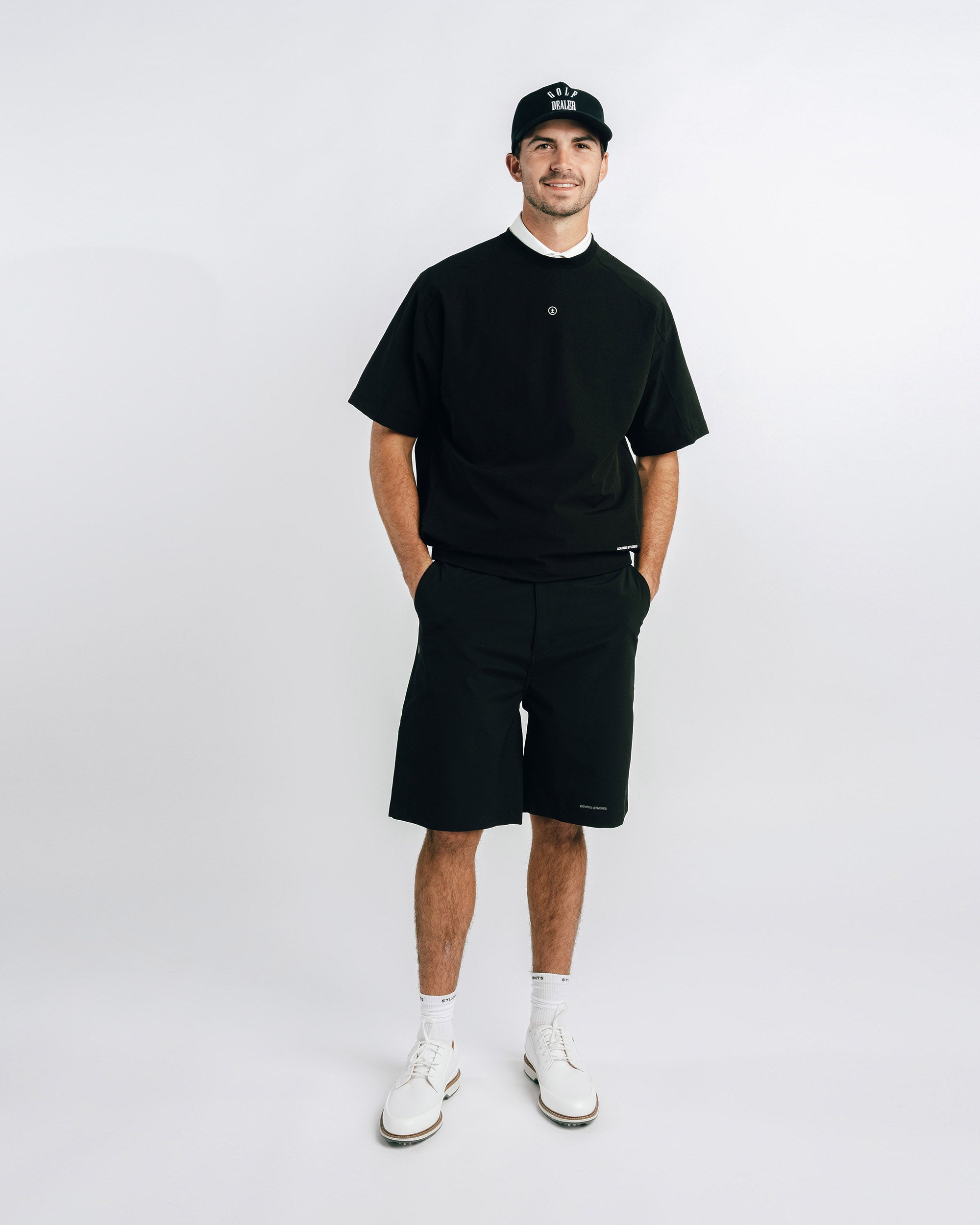 Man wearing a black t-shirt, shorts, and cap on a white background