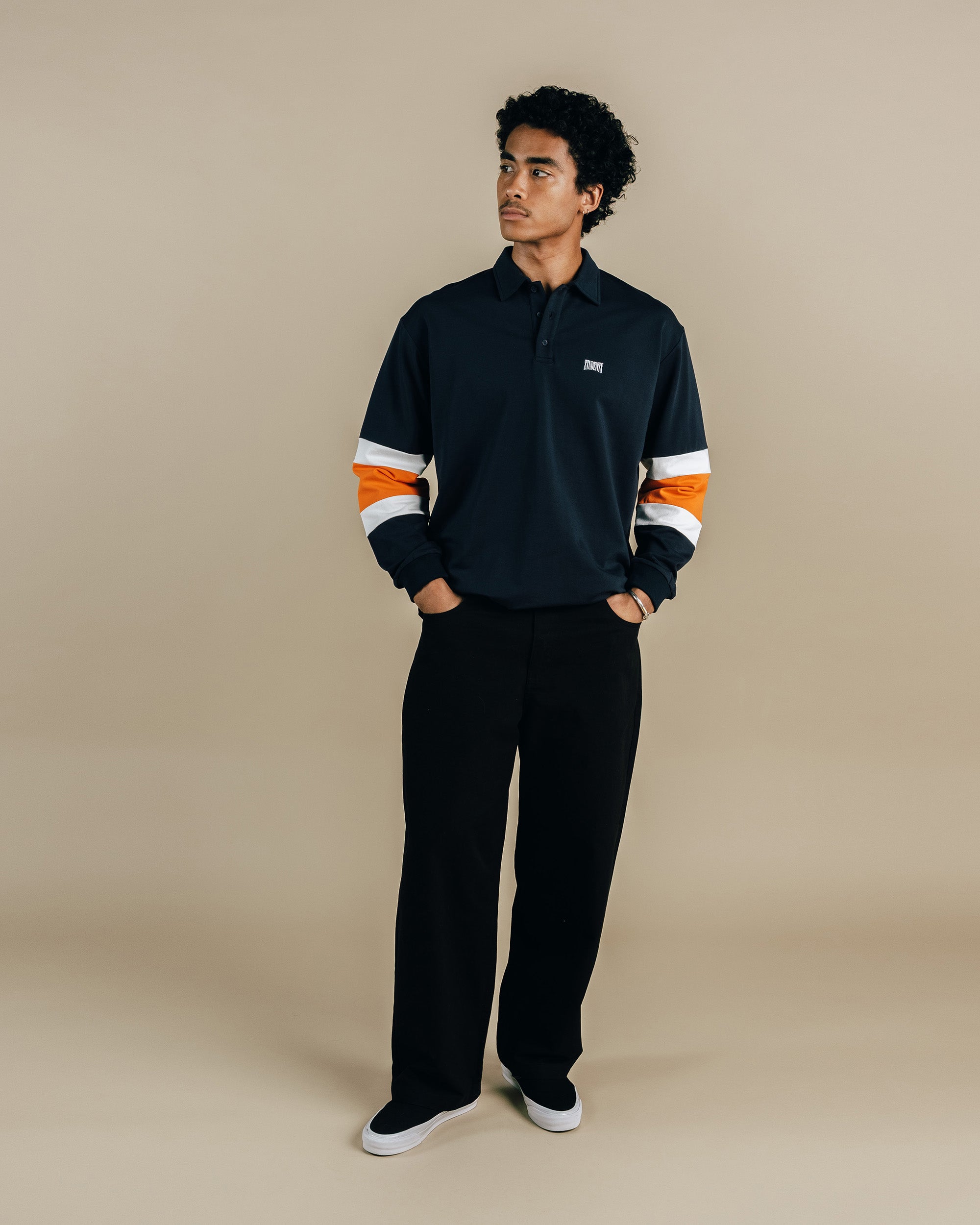 Person wearing a black quarter-zip sweatshirt with orange and white stripes on a beige background