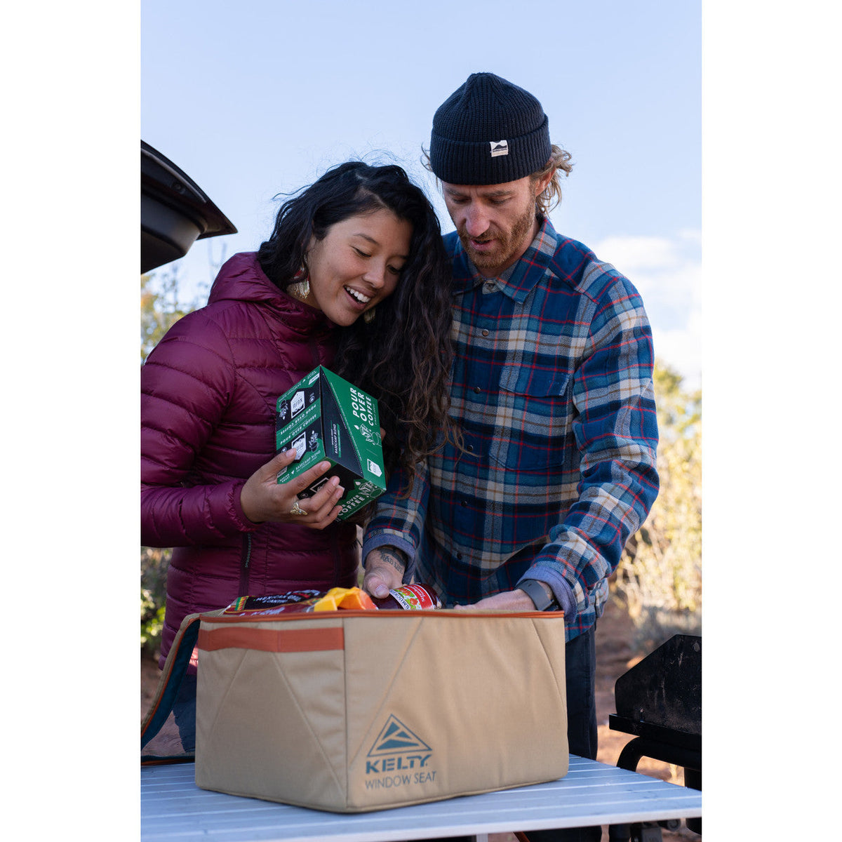 Couple placing gear into Kelty Window Seat storage bin