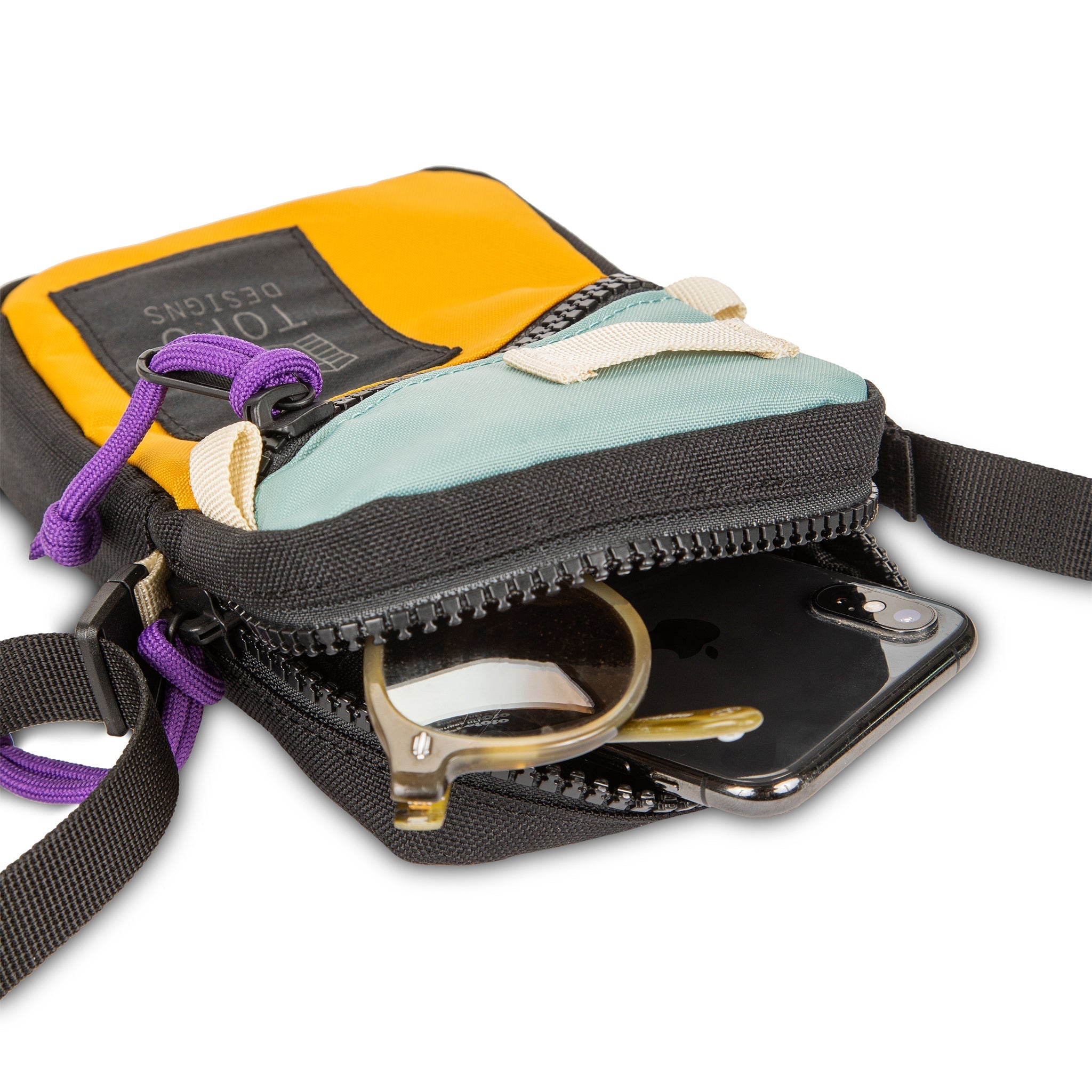 Topo Designs Mini Shoulder Bag crossbody travel purse in Sage Mustard detail showing zipper opening with sunglasses and iPhone inside.