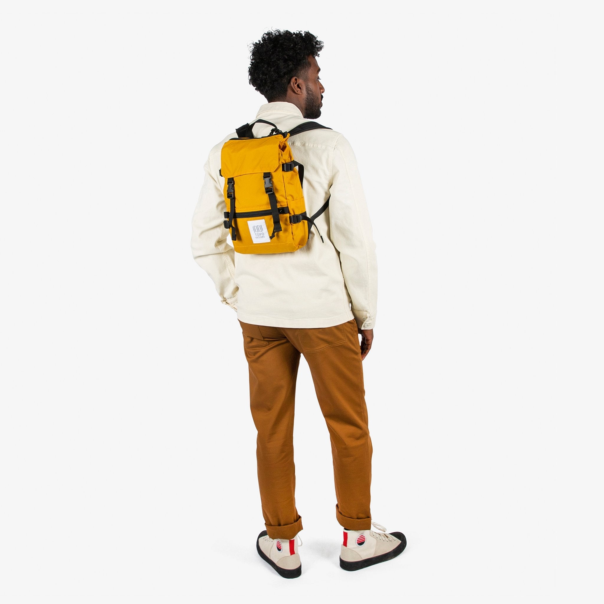 Topo Designs Rover Pack Mini backpack in Mustard yellow worn by model with backpack straps.
