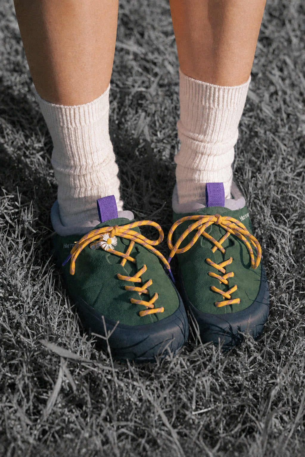 Green shoes with yellow laces worn on grass
