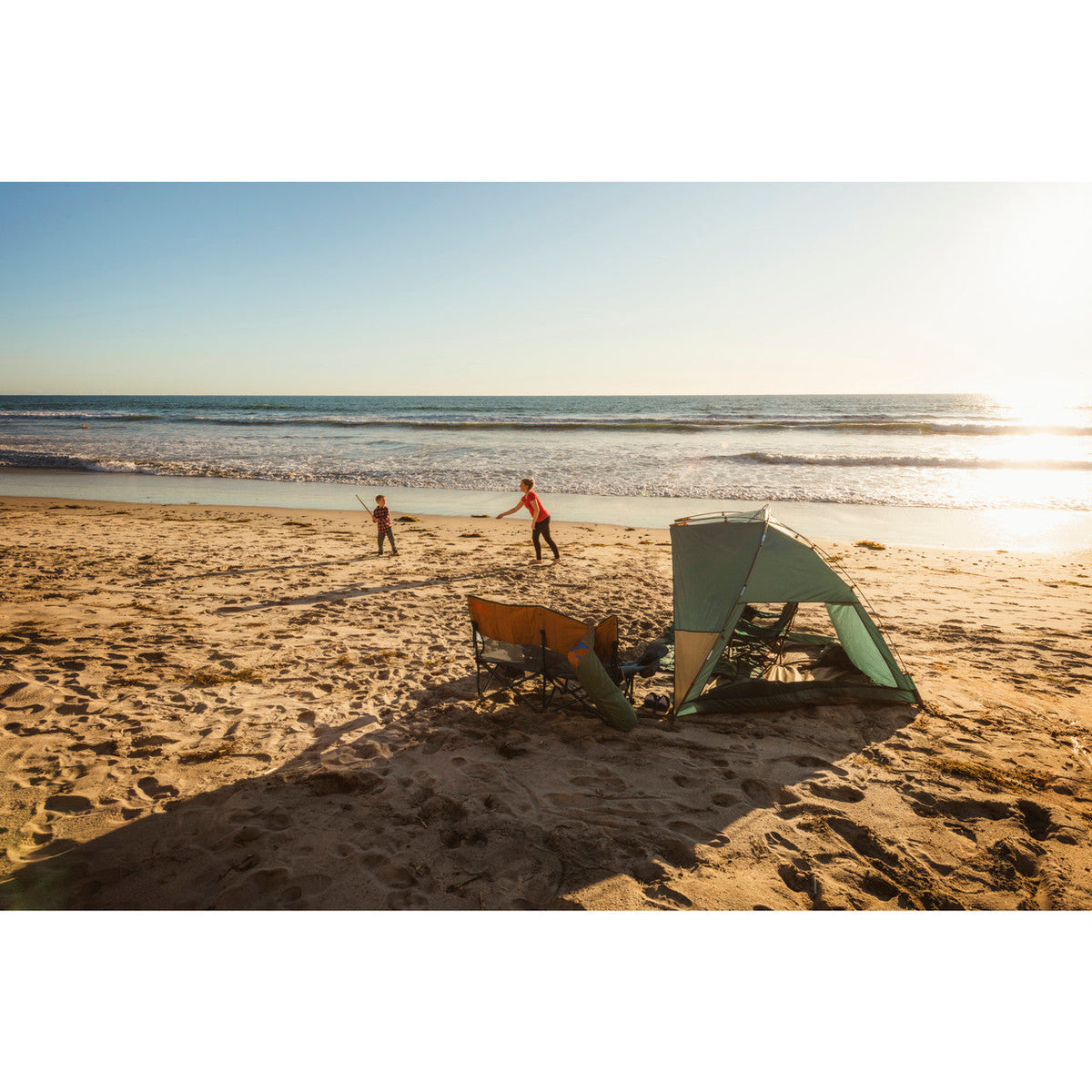 Mother and child plying at beach, Cabana shelter in the foreground. 