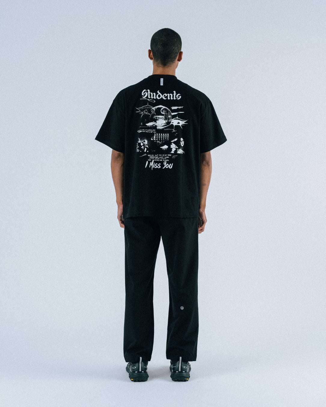 Person wearing a black t-shirt with graphic design on the back against a white background