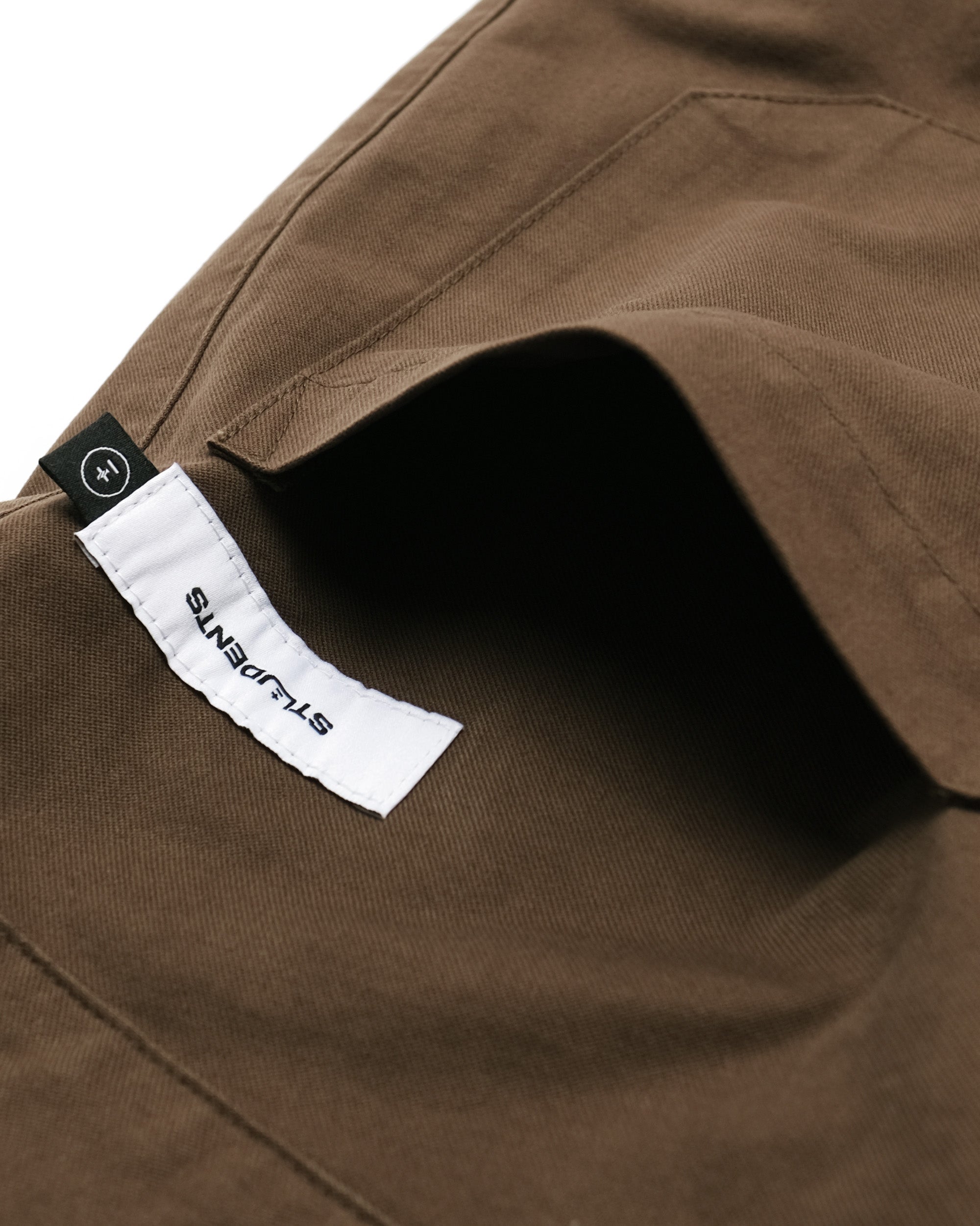 Close-up of a brown fabric with a visible brand label on a white background