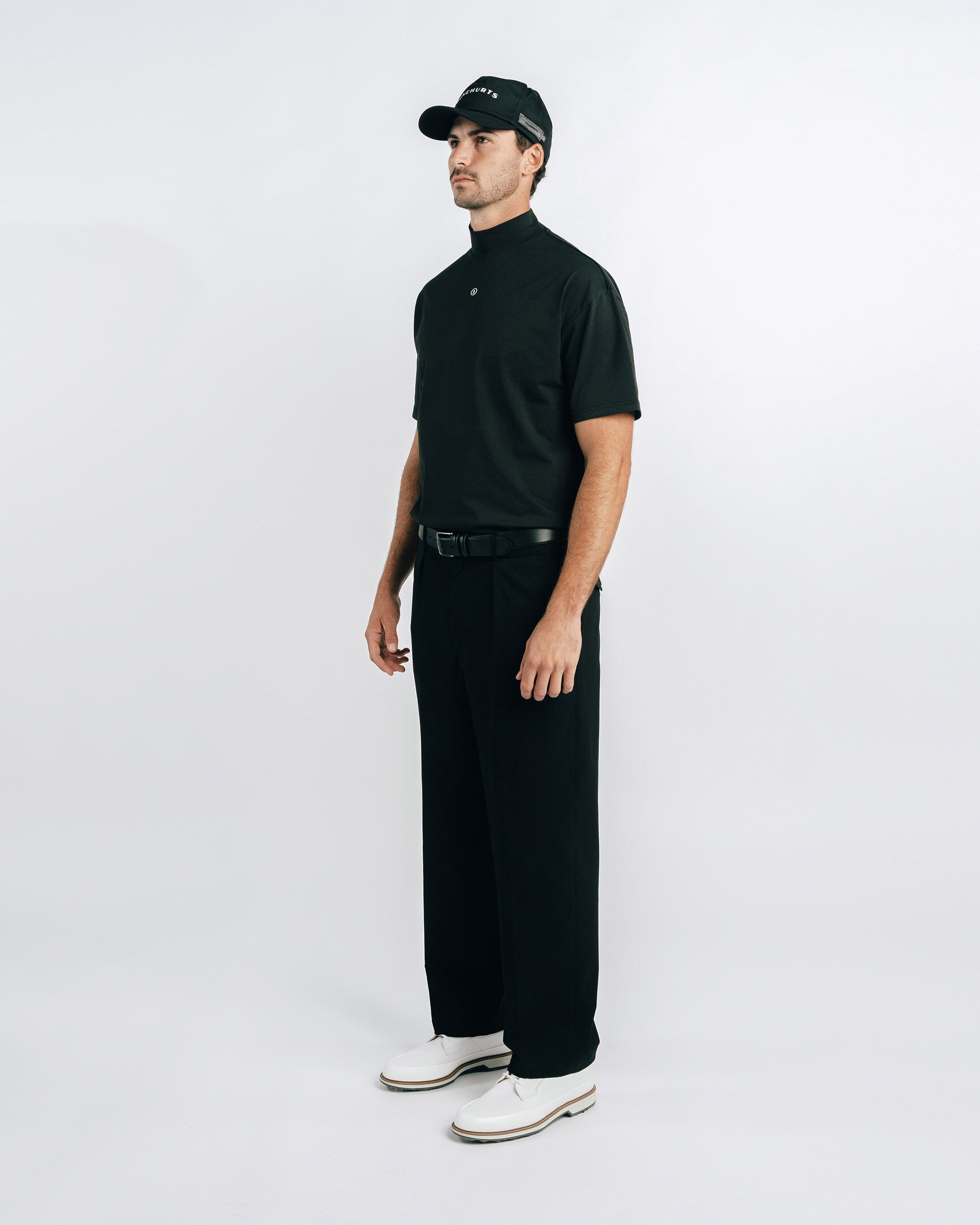 Man wearing a black outfit with a cap on a white background