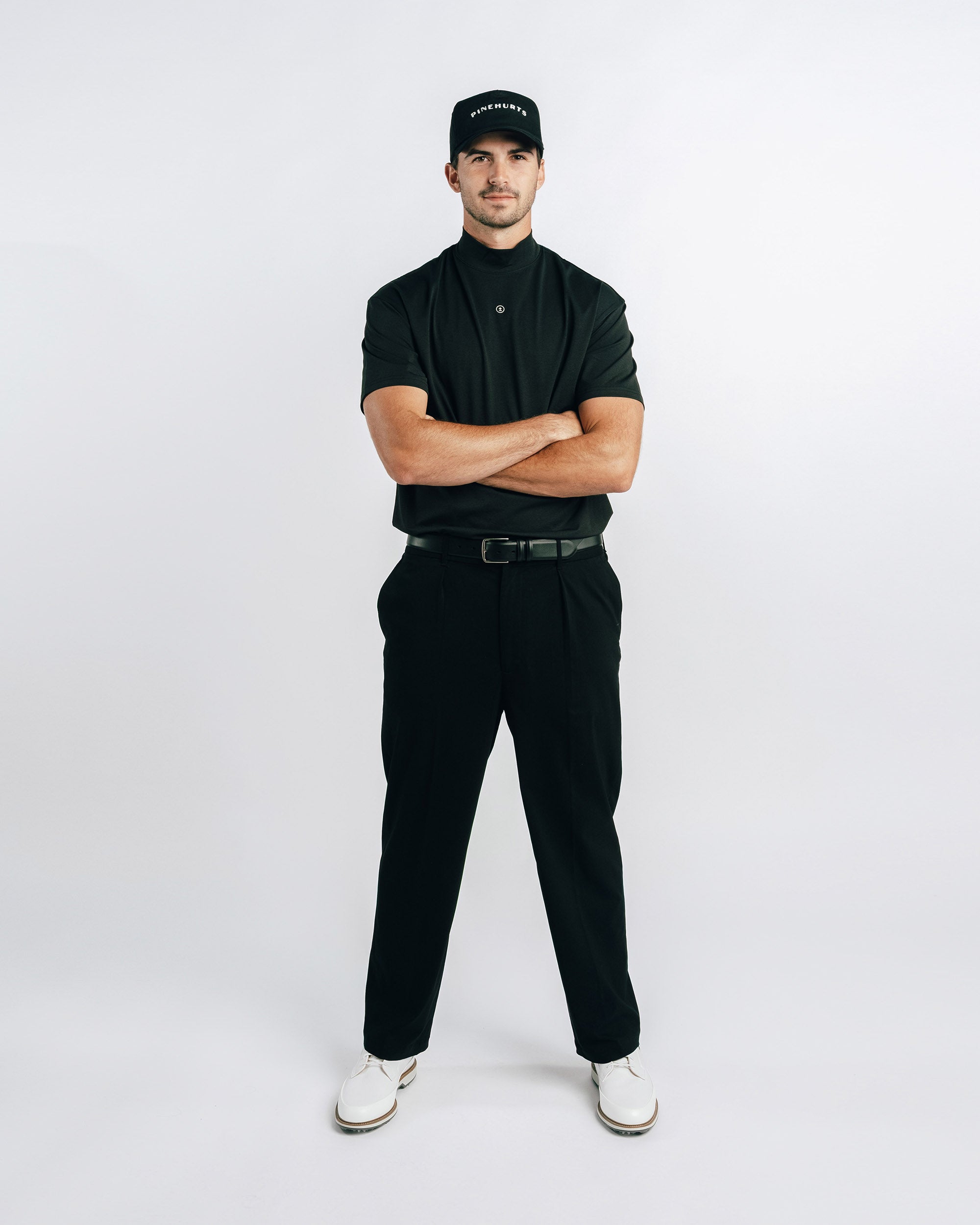 Man wearing a black outfit with a cap on a white background