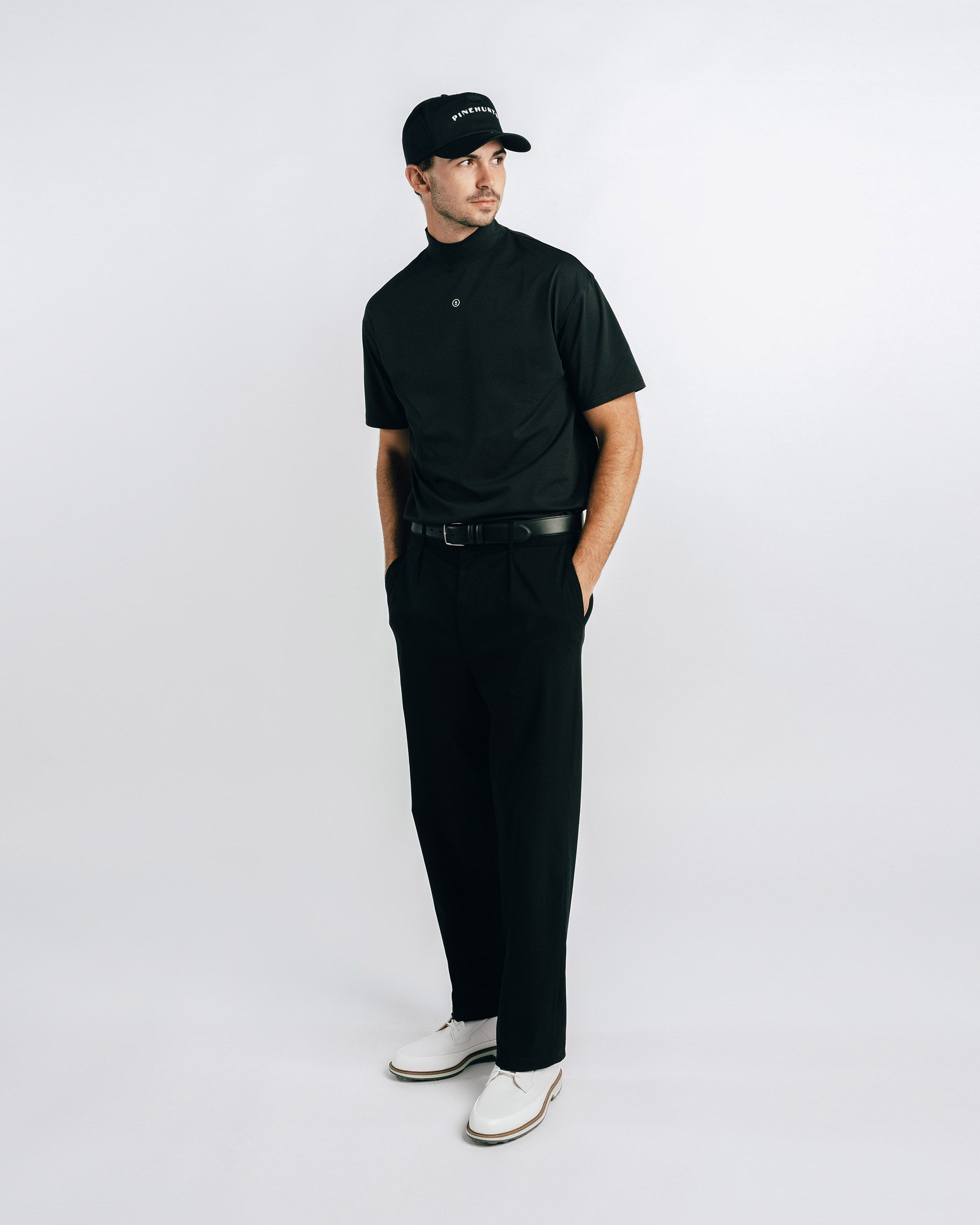 Man wearing a black t-shirt, black pants, and white shoes on a white background