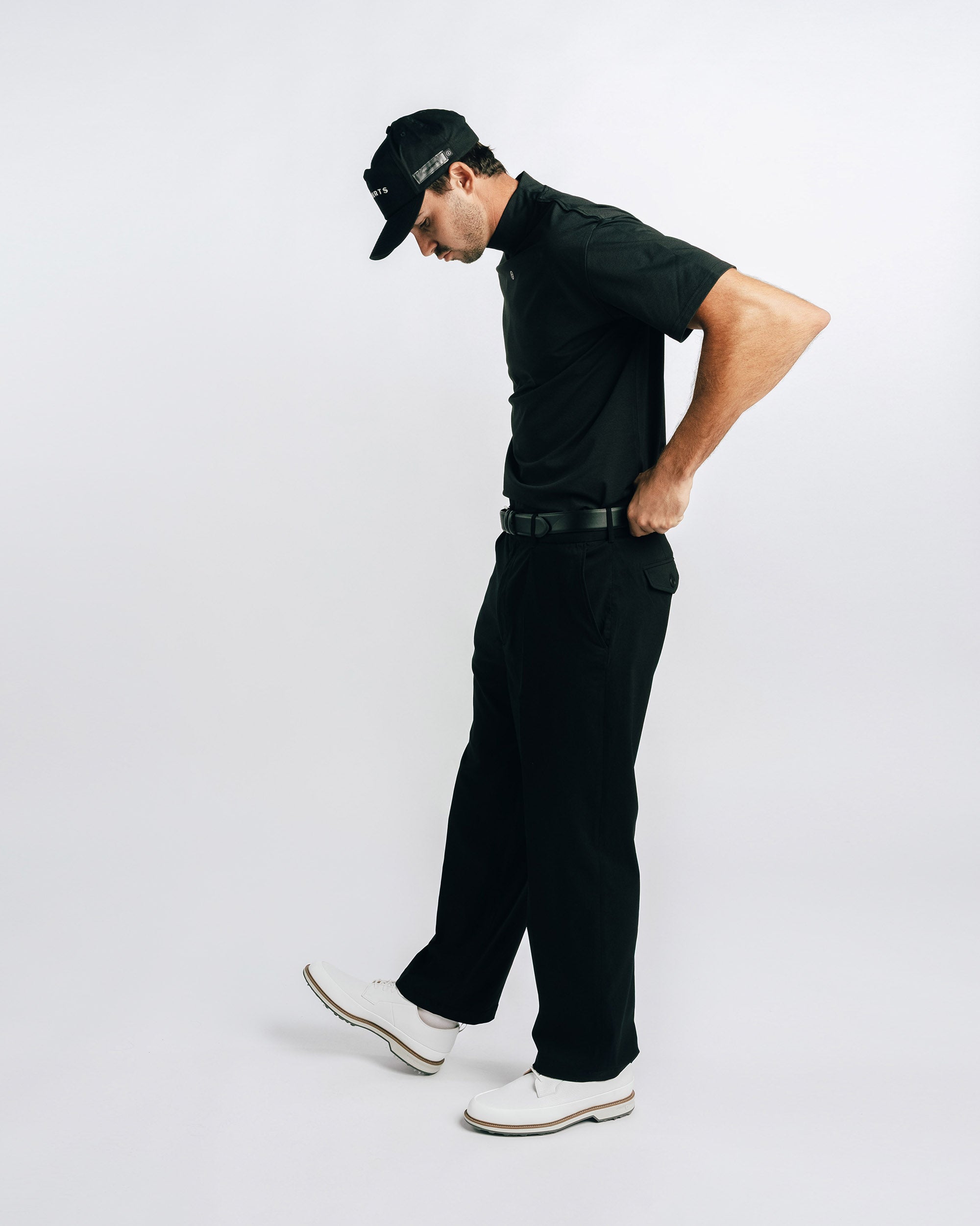 Man wearing a black outfit with a cap on a white background