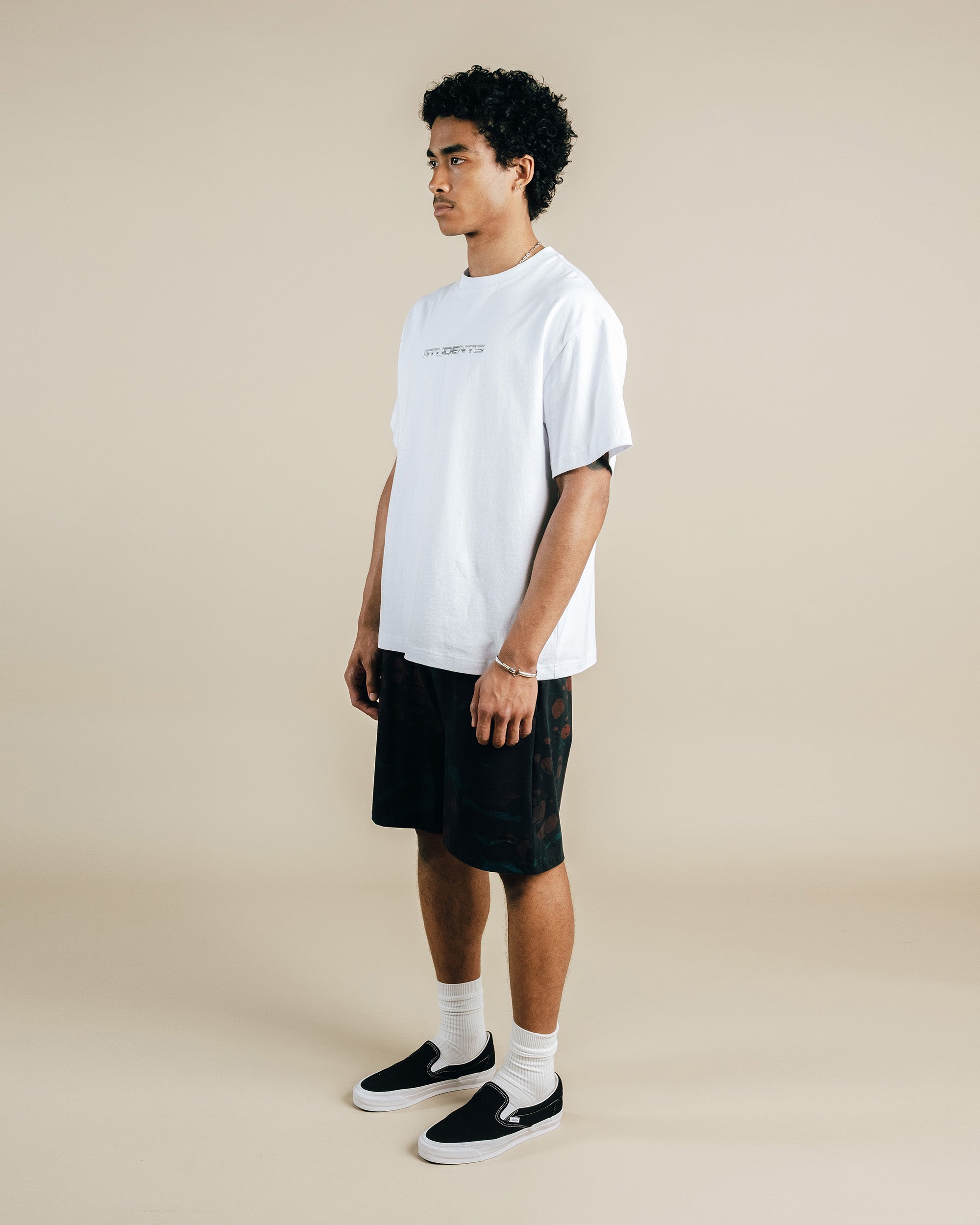 Person wearing a white t-shirt and black shorts on a beige background