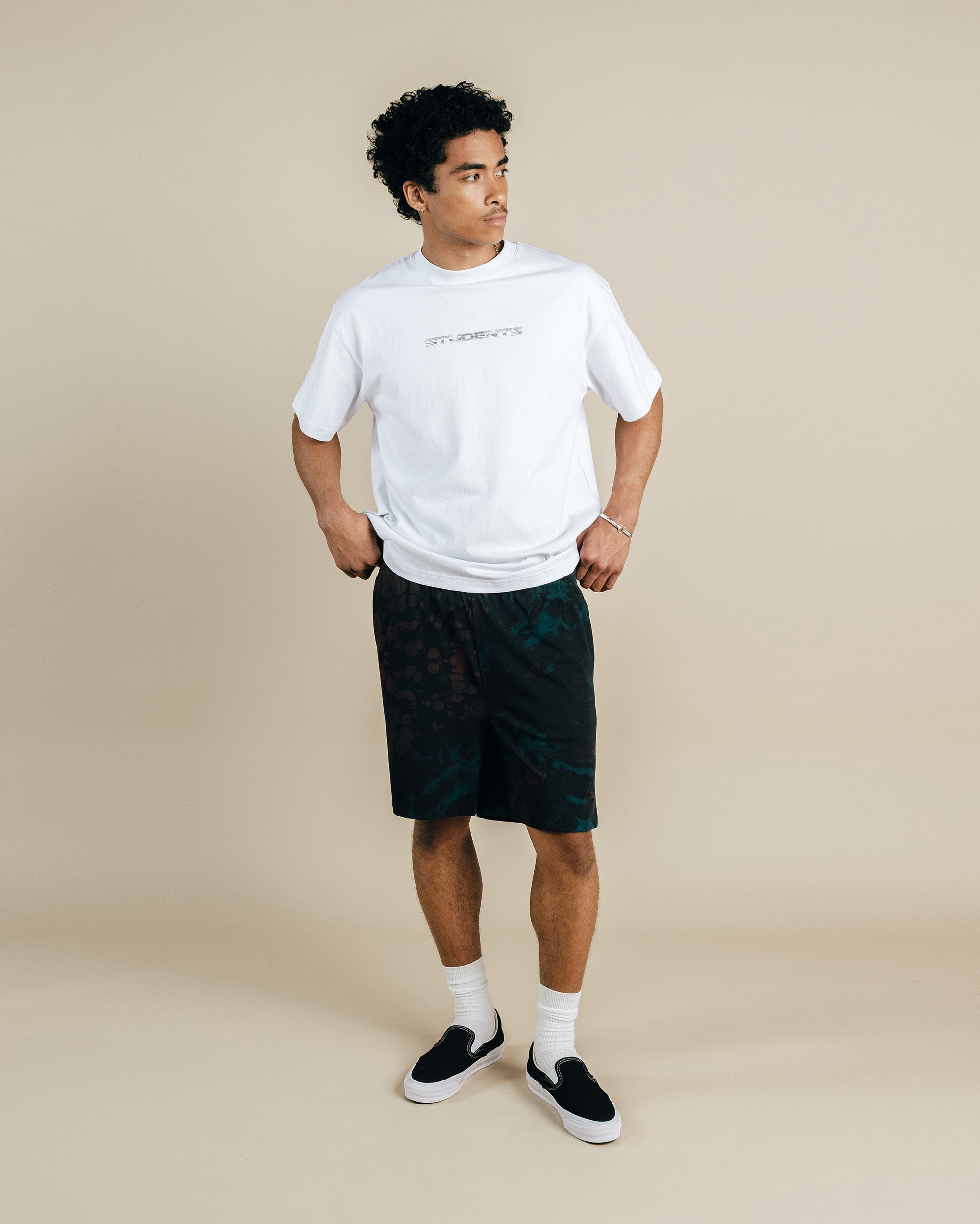 Man wearing a white t-shirt and black shorts on a beige background