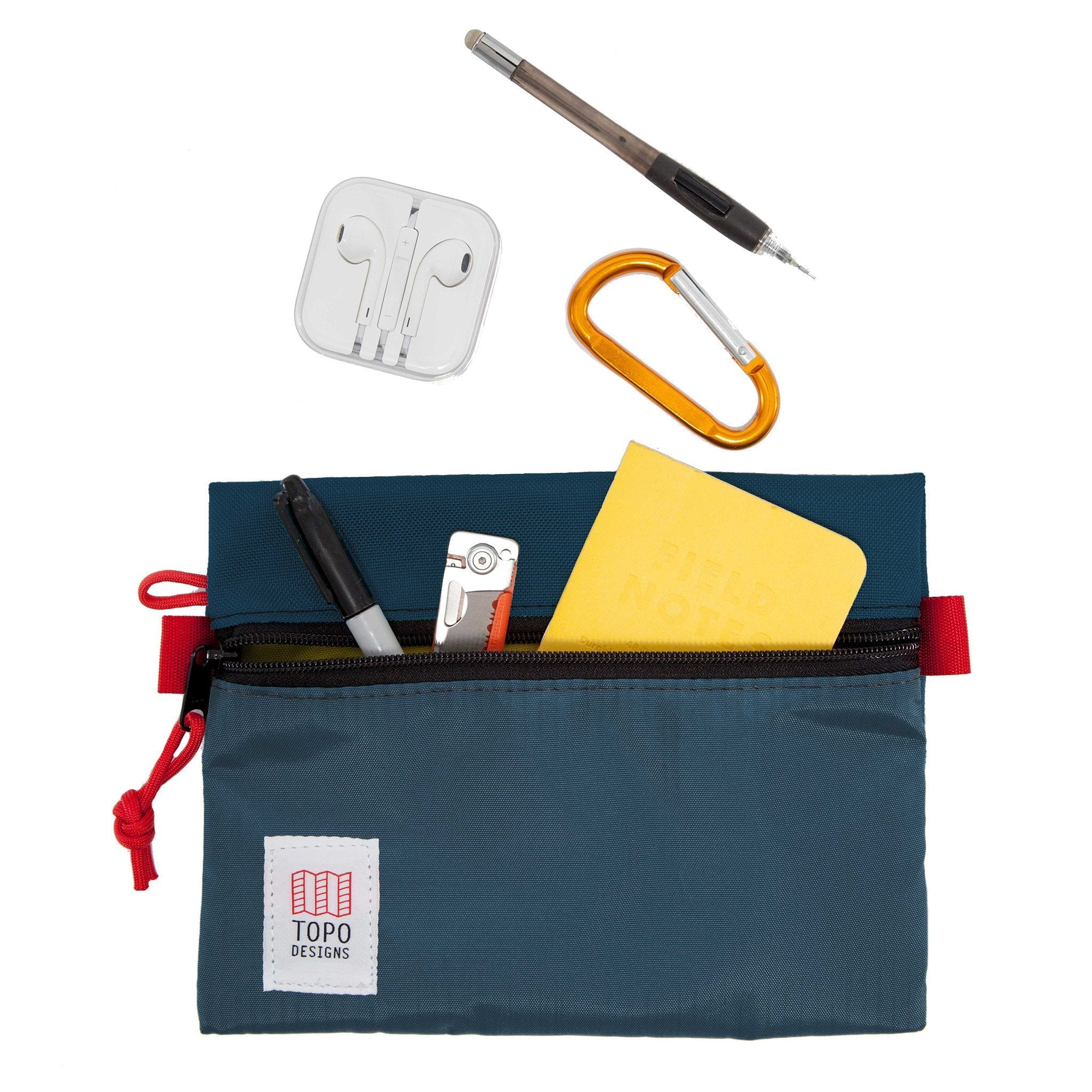 Detail shot of Topo Designs Accessory bags, organizer pouches for travel, showing pencils, headphones, and notebook inside the medium navy blue bag.
